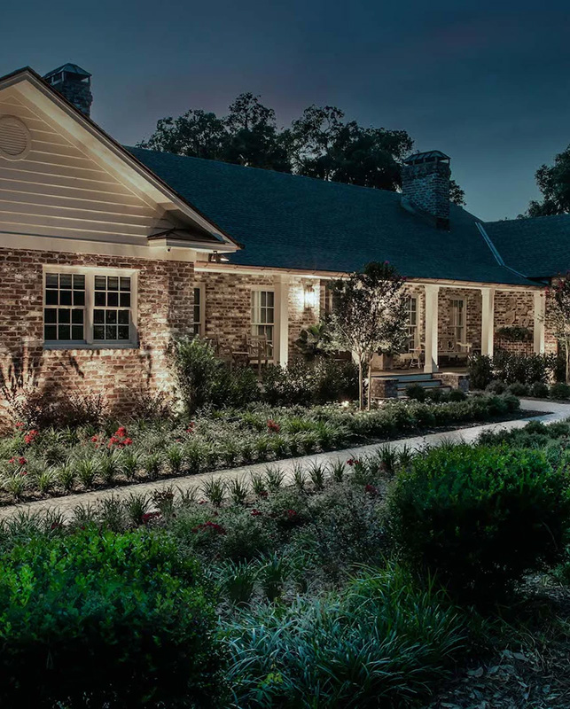 brick home with small bushes and plants with exterior lighting